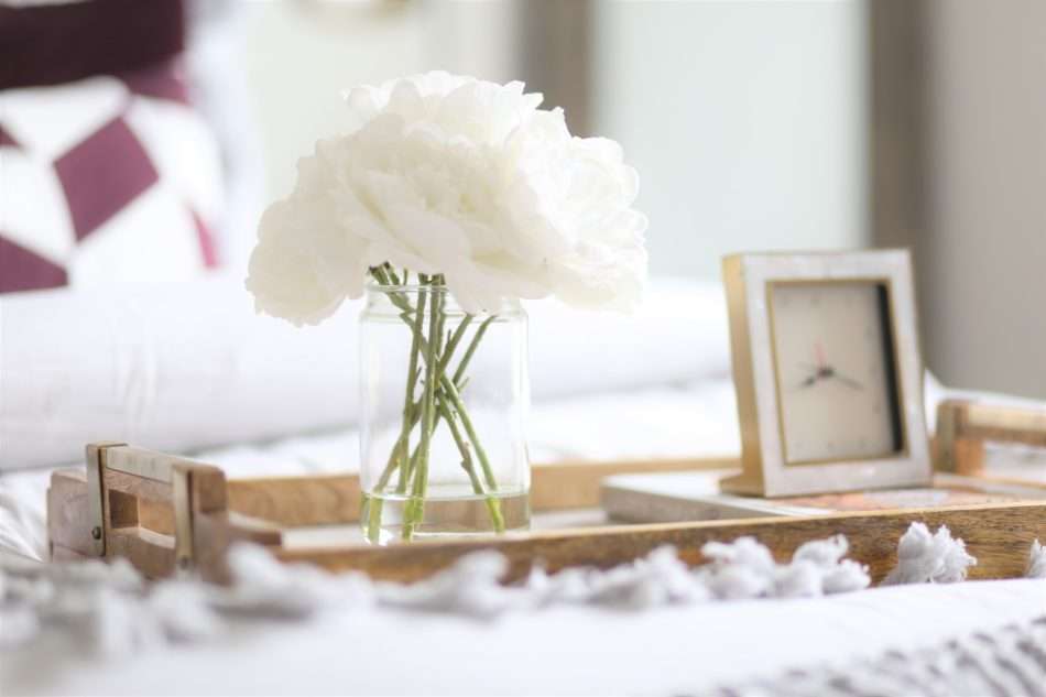 feminine guestroom, girl guestroom, guestroom, boutique style guest room, colorful guestroom, accent chair in guest room, black bed, wooden bed, floor mirror, textured bedding, guest bedroom decor, table books, books on coffee table, books on table, coffee table decor, how to accessorize like a pro, boxwood on table, mixing materials, coffee table accessories, accessorizing, how to accessorize, how to layer books, how to decorate like a pro, how to decorate with books, display case, agate stone, agate stone in display case, decorating in odd numbers, the rules of three, how to decorate in odd numbers, living room decor, mirrored credenza, balanced living room, luxury living room, mixed materials, vignette, floor lamp, brass floor lamp, navy sofa, navy sofa with chaise, pillow in basket, black basket, peonies, vases, silver vases, silver clay vases, wood tray, mixing metals