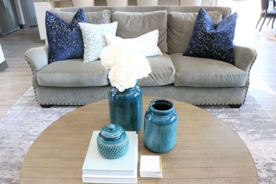 blue accessories, blue decor, living room with blue decor, gray sofa, living room decor, living room, neutral living room, pops of blue, blue colors in living room, blue pillows, blue vases, wooden coffee table