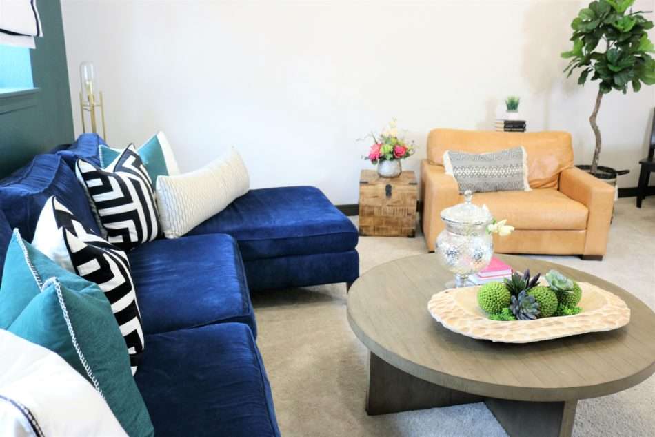 colorful family room, navy sofa, blue sofa, roman shades, black roman shades, green wall, green wall with navy sofa, tripod lamp, coffee table decor